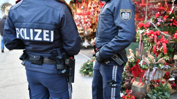 Zwei Polizisten stehen vor einem Weihnachtsstand.