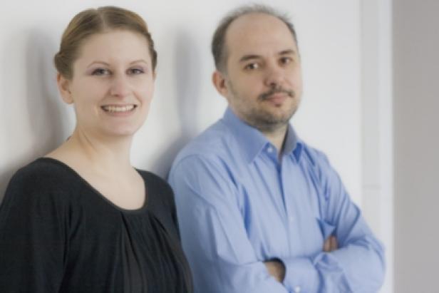 Eine Frau und ein Mann stehen vor einer weißen Wand.