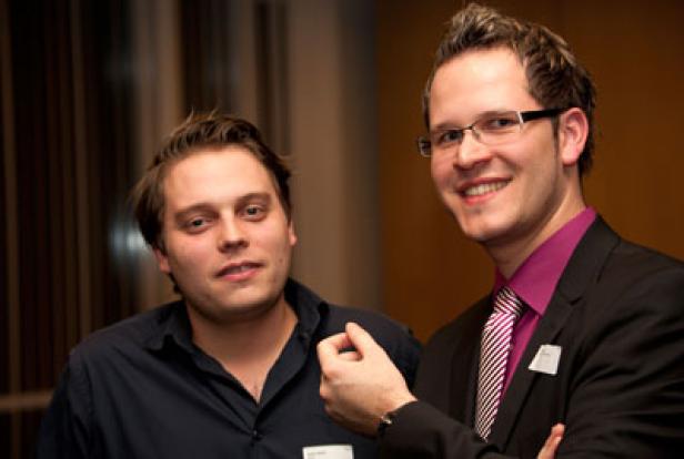 Zwei Männer posieren lächelnd für ein Foto.