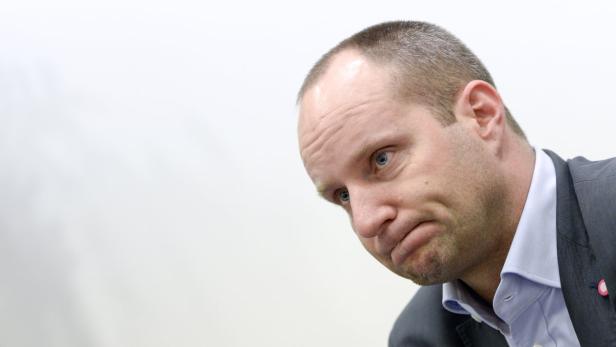 Ein Mann mit Anzug schaut nachdenklich nach unten.