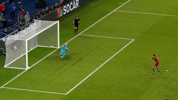 Ein Fußballspieler schießt einen Elfmeter, während der Torwart versucht, den Ball abzuwehren.