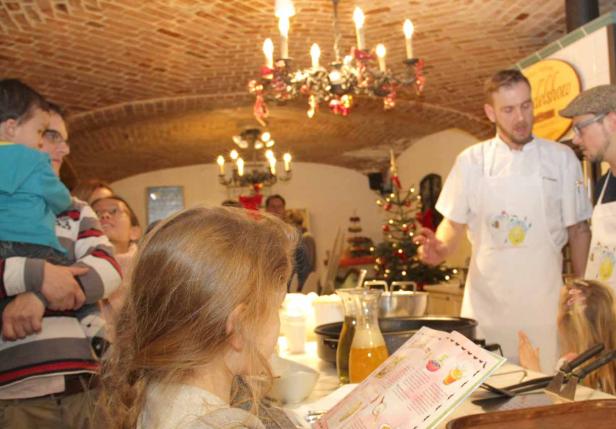 Eine Gruppe von Menschen versammelt sich in einem Raum mit einem Weihnachtsbaum und einem Koch.