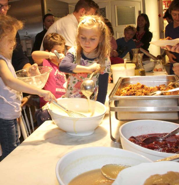 Kinder helfen beim Zubereiten von Speisen an einem Buffet.