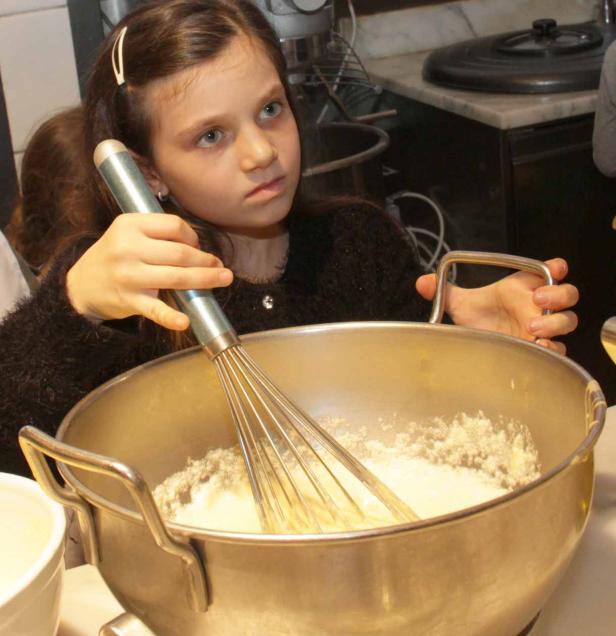 Ein junges Mädchen rührt Teig in einer großen Schüssel mit einem Schneebesen.