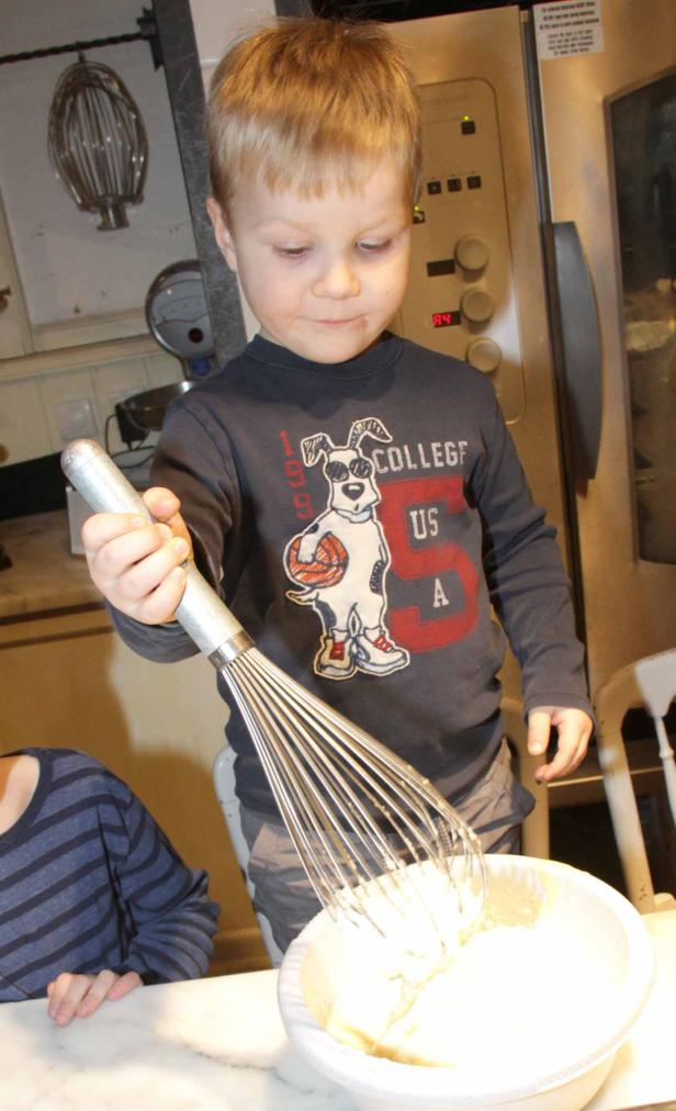 Ein Junge rührt mit einem Schneebesen Teig in einer Schüssel.