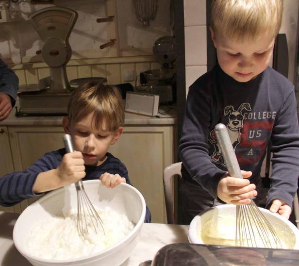 Zwei Kinder rühren Teig in Schüsseln mit Schneebesen.