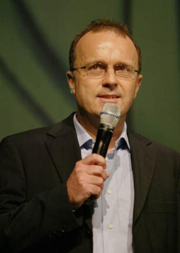 Ein Mann mit Brille spricht in ein Mikrofon.