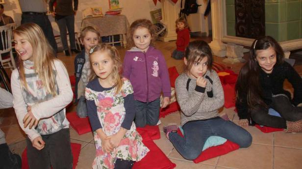 Eine Gruppe Kinder sitzt auf Kissen und hört aufmerksam zu.