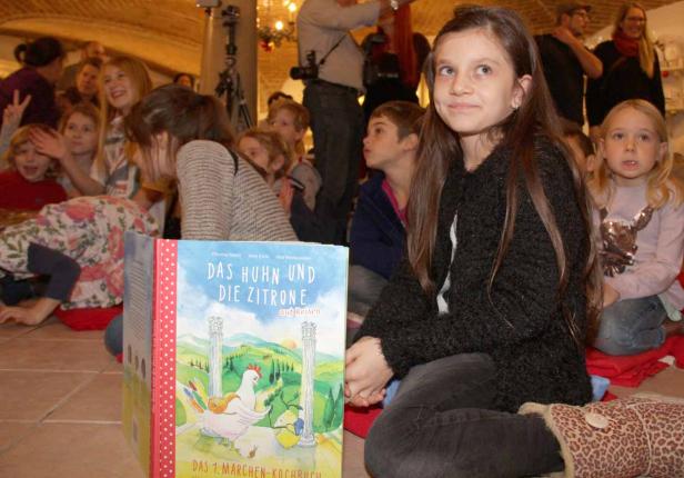 Eine Gruppe Kinder sitzt vor dem Buch „Das Huhn und die Zitrone auf Reisen“.