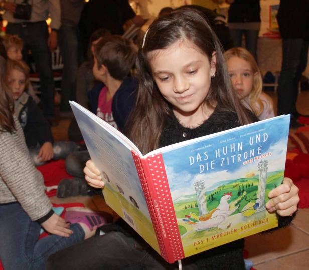 Ein Mädchen liest das Buch „Das Huhn und die Zitrone auf Reisen“ vor Publikum.