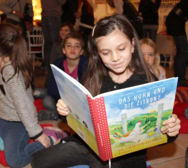 Ein junges Mädchen liest das Buch „Das Huhn und die Zitrone auf Reisen“.