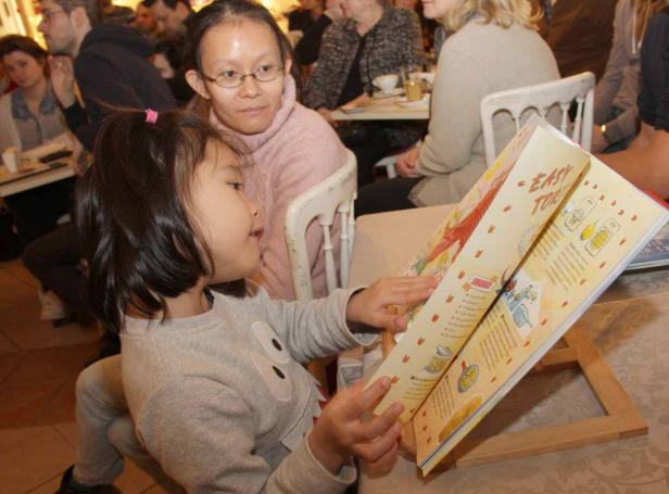 Ein kleines Mädchen liest ein Kochbuch mit dem Titel „Easy Tort“.