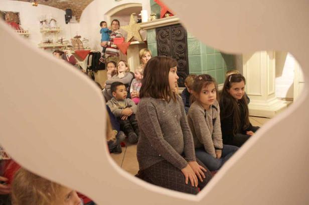 Eine Gruppe Kinder sitzt auf dem Boden und schaut aufmerksam zu.