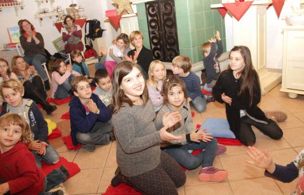 Eine Gruppe Kinder sitzt auf dem Boden und klatscht in die Hände.