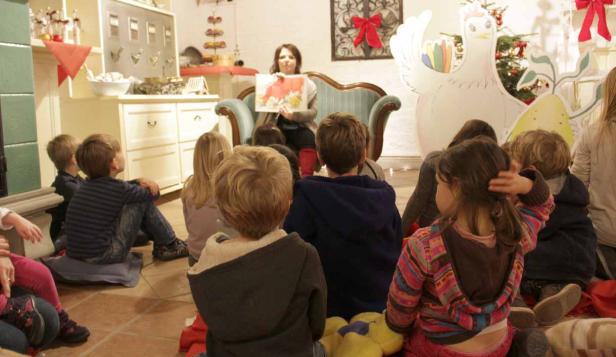 Eine Frau liest einer Gruppe von Kindern eine Geschichte vor.