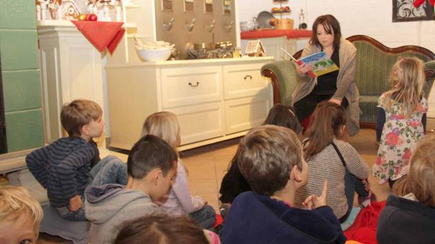Eine Frau liest einer Gruppe von Kindern in einem Raum eine Geschichte vor.