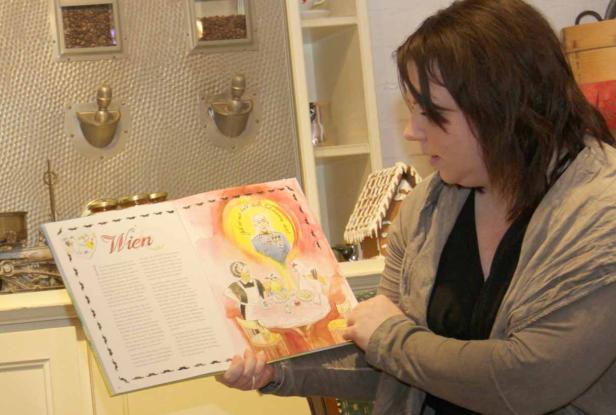 Eine Frau liest in einem Buch über Wien mit einer Illustration von Kaiser Franz Joseph I..