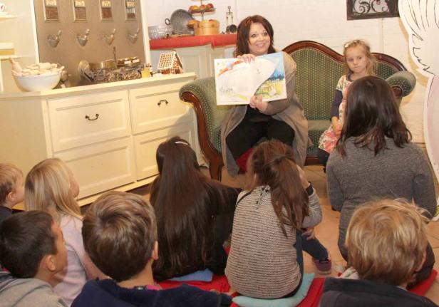 Eine Frau liest einer Gruppe von Kindern aus einem Bilderbuch vor.