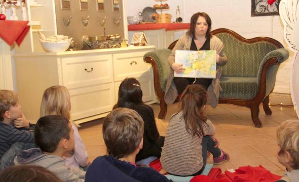 Eine Frau liest einer Gruppe von Kindern aus einem Buch vor.