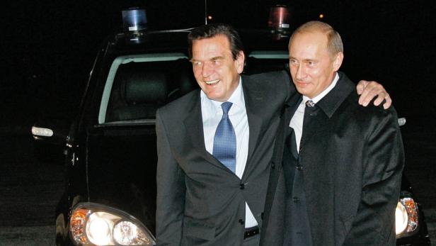 Gerhard Schröder und Wladimir Putin stehen vor einem schwarzen Auto.