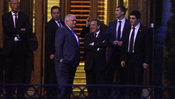 Gerhard Schröder steht mit anderen Personen vor einem Gebäude.