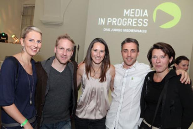 Eine Gruppe von fünf Personen posiert vor einem „Media in Progress“-Logo.