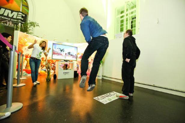 Ein Mann springt vor einem Bildschirm, während er ein Kinect-Spiel spielt.
