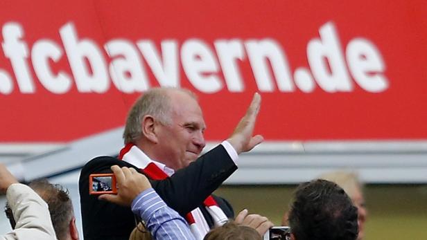 Uli Hoeneß winkt vor einem Banner des FC Bayern München.