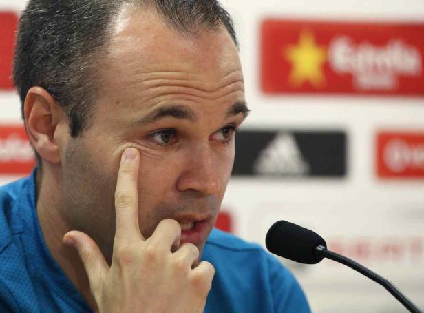 Andrés Iniesta spricht auf einer Pressekonferenz und berührt sein Auge.