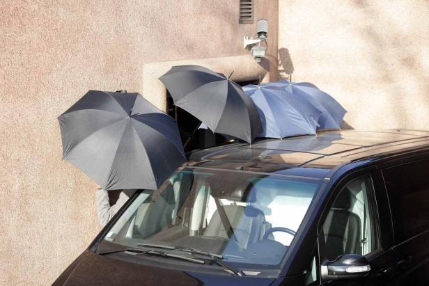 Mehrere Regenschirme liegen auf dem Dach eines schwarzen Autos.