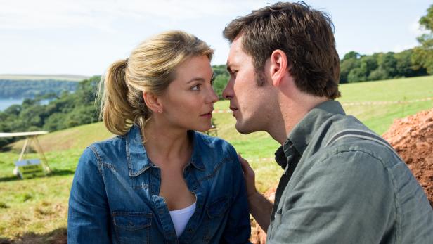 Ein Paar steht sich auf einer Wiese gegenüber und schaut sich in die Augen.