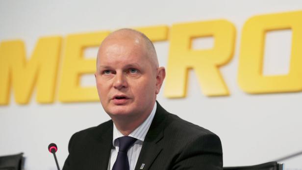 Ein Mann im Anzug spricht vor dem gelben Metro-Logo.