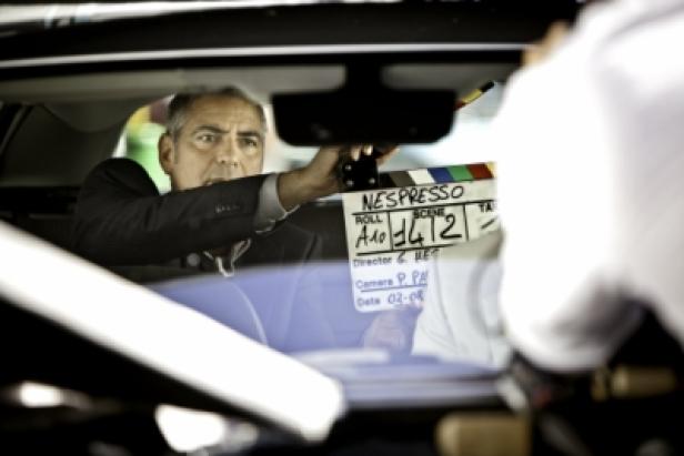 George Clooney hält eine Nespresso-Filmklappe in einem Auto.