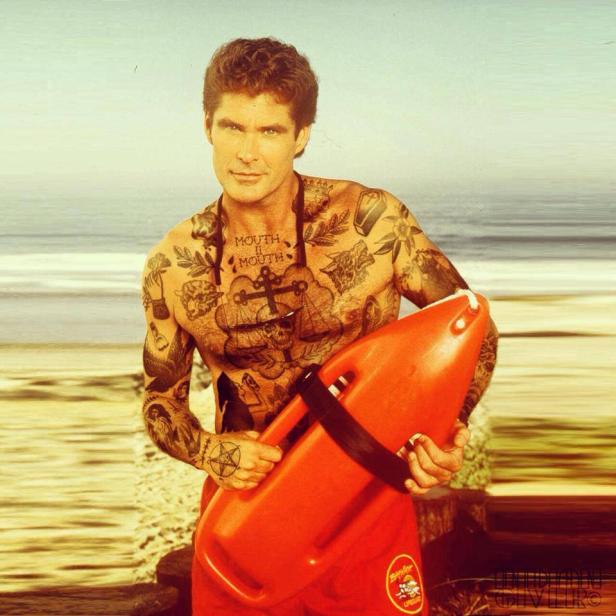 David Hasselhoff als tätowierter Rettungsschwimmer mit Rettungsboje am Strand.