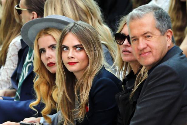 Cara Delevingne, Kate Moss und andere sitzen in der ersten Reihe einer Modenschau.