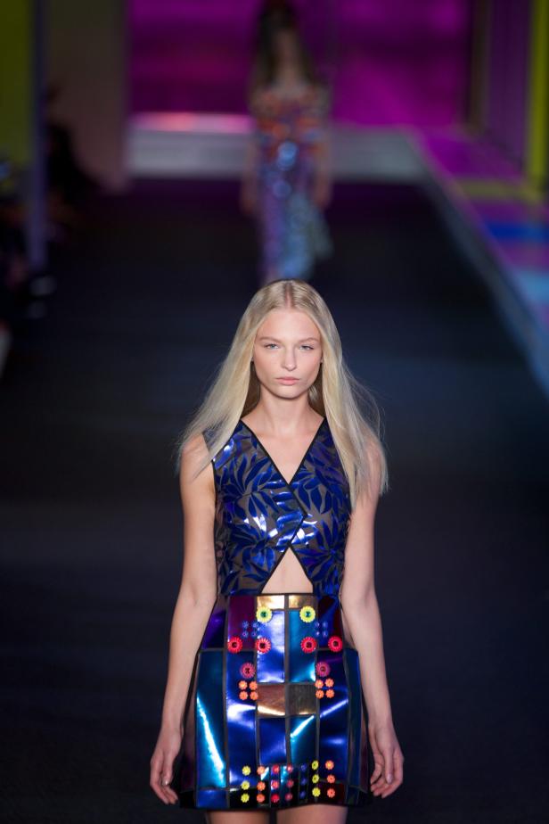 Ein blondes Model auf dem Laufsteg trägt ein blaues Kleid mit floralen Mustern.