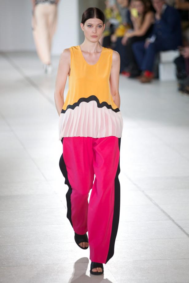 Eine Frau in einem farbenfrohen Outfit läuft über einen Laufsteg.