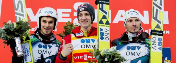 Drei Skispringer stehen mit ihren Skiern und Pokalen auf dem Siegerpodest.