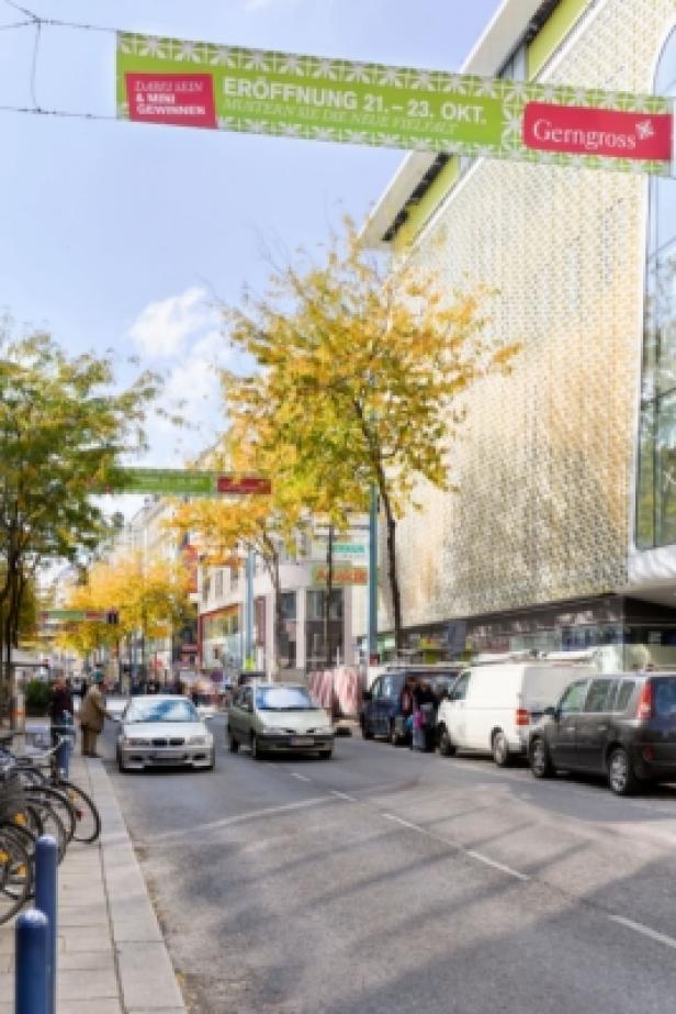Eine Straße in der Stadt mit parkenden Autos und einem Gerngross-Banner über der Straße.