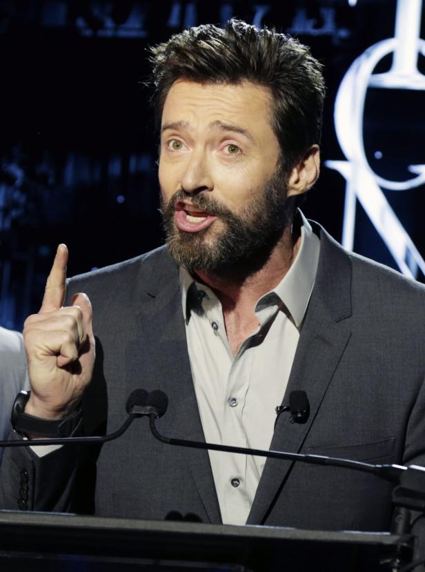 Hugh Jackman spricht bei einer Veranstaltung und hebt warnend den Finger.