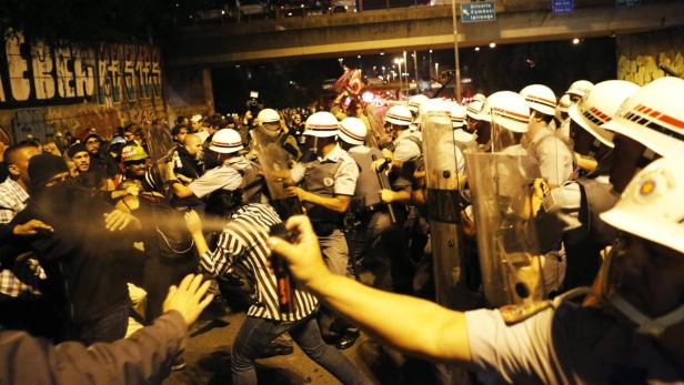 Bei einer Demonstration sprühen Polizisten mit Schutzschilden Pfefferspray in eine Menschenmenge.