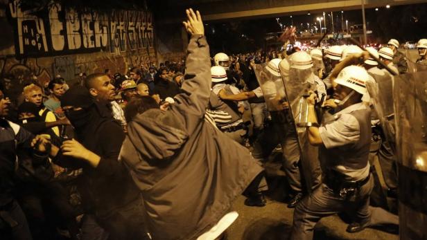 Bei einer nächtlichen Demonstration stehen sich Demonstranten und Polizisten mit Schilden gegenüber.
