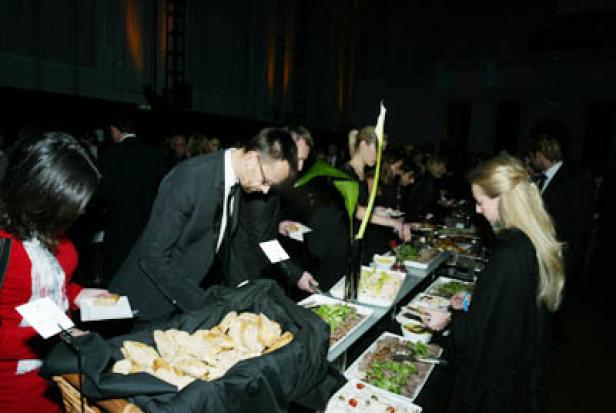 Gäste bedienen sich an einem Buffet mit Brot und Salaten.