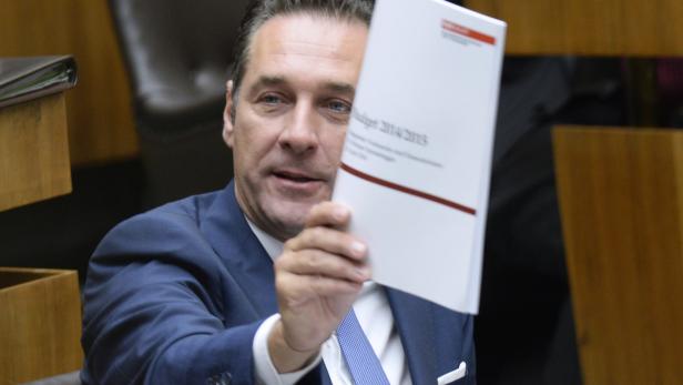 Ein Mann im Anzug hält ein Dokument mit der Aufschrift „Budget 2014/2015“ hoch.