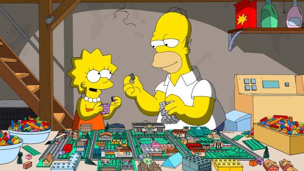 Homer und Lisa Simpson bauen gemeinsam eine Stadt aus Legosteinen.