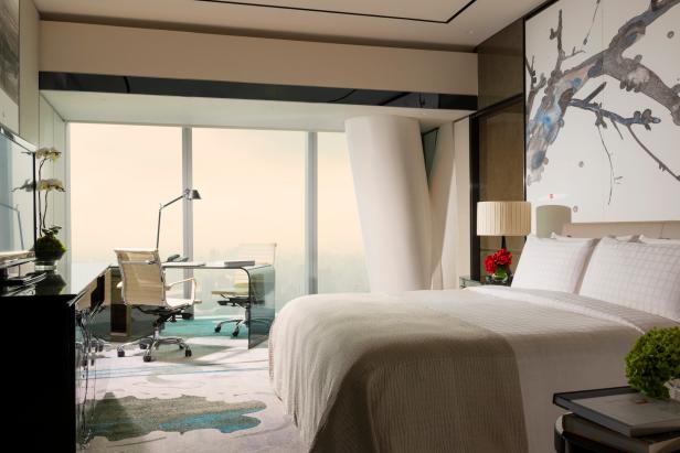 Ein helles Hotelzimmer mit Schreibtisch, Stühlen und einem großen Fenster mit Ausblick.