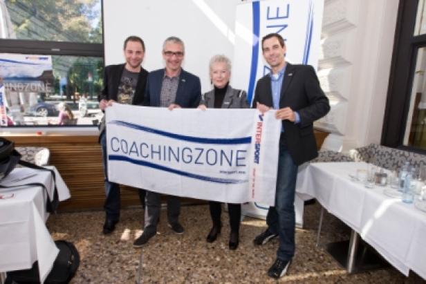 Vier Personen halten ein Banner mit der Aufschrift „Coachingzone“.