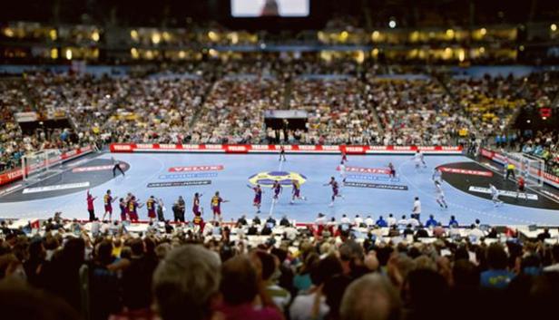 Ein Handballspiel in einer Halle mit vielen Zuschauern.