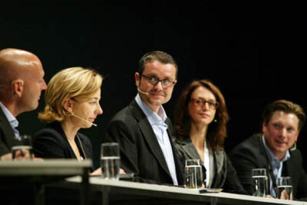 Fünf Personen sitzen an einem Tisch während einer Podiumsdiskussion.