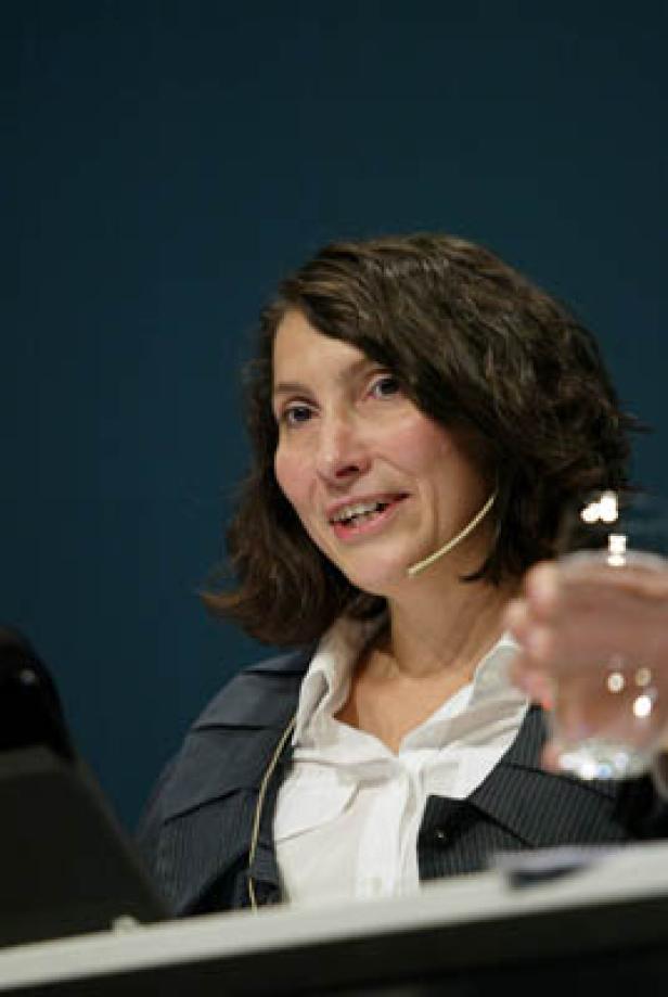 Eine Frau mit Mikrofon spricht bei einer Konferenz.